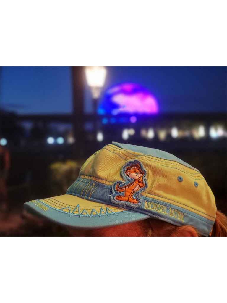 Green Munk cadet hat displayed outdoors at night with colorful lights behind